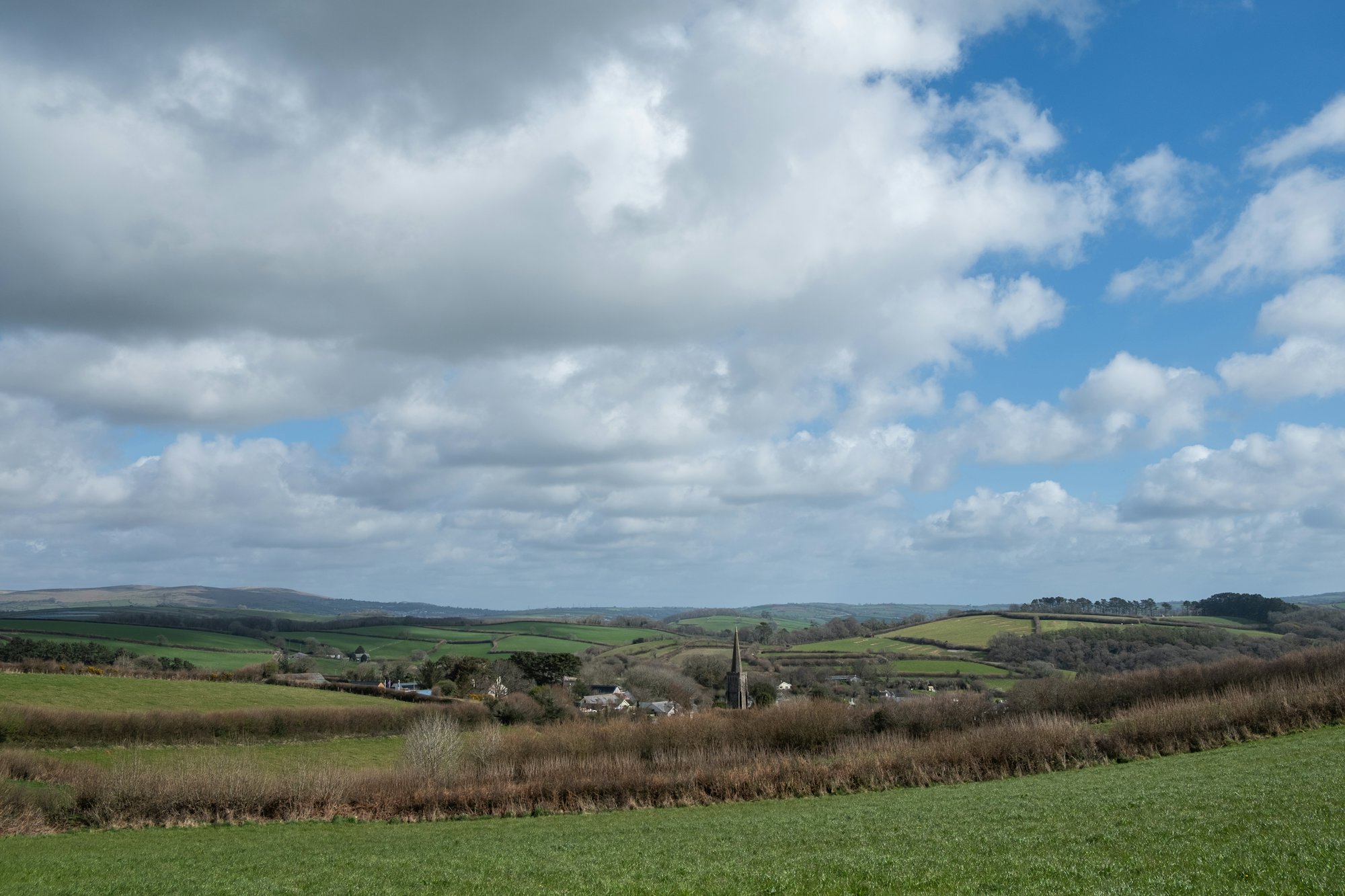 Green fields and hedgerows under a cloudy sky in the English countryside