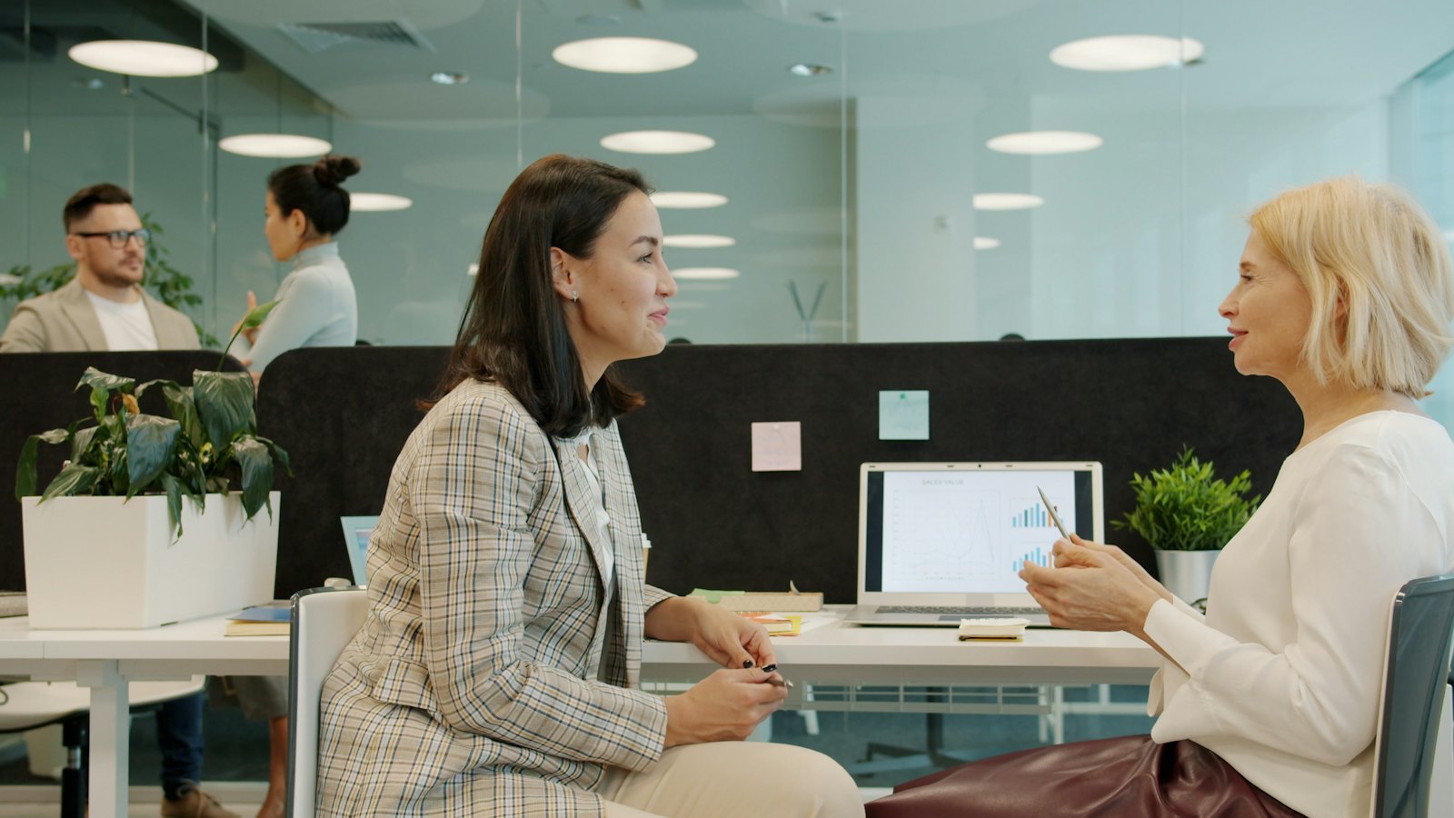 Two colleagues talking across a desk in a bright office